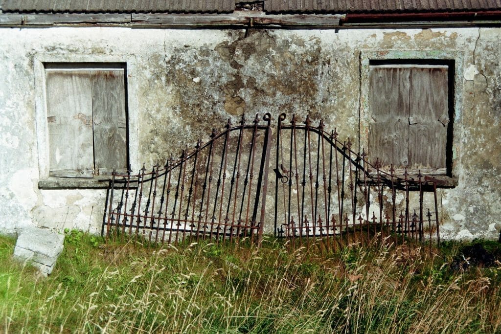 Roadtrip durch Irland: Ein altes geschmiedetes Tor rostet vor einem verlassenen Cottage.